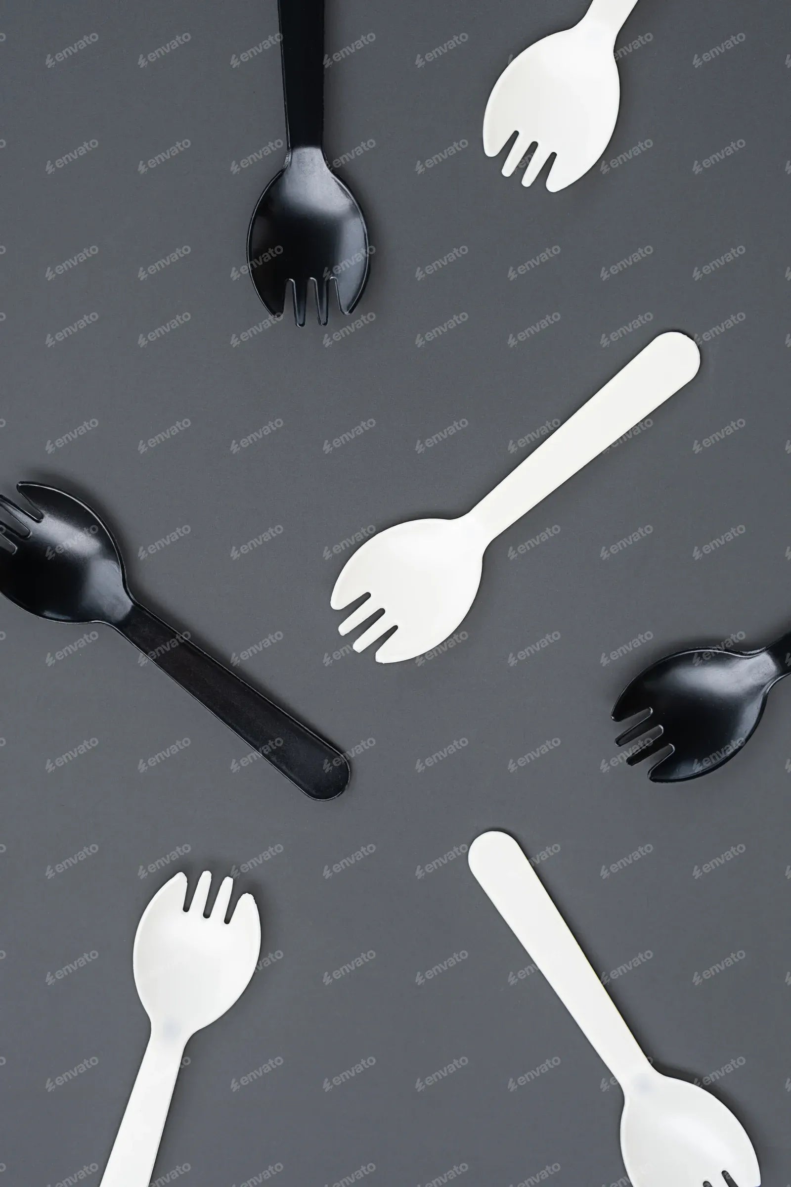 Black and white plastic forks on gray background. Disposable cutlery and minimalism concepts.