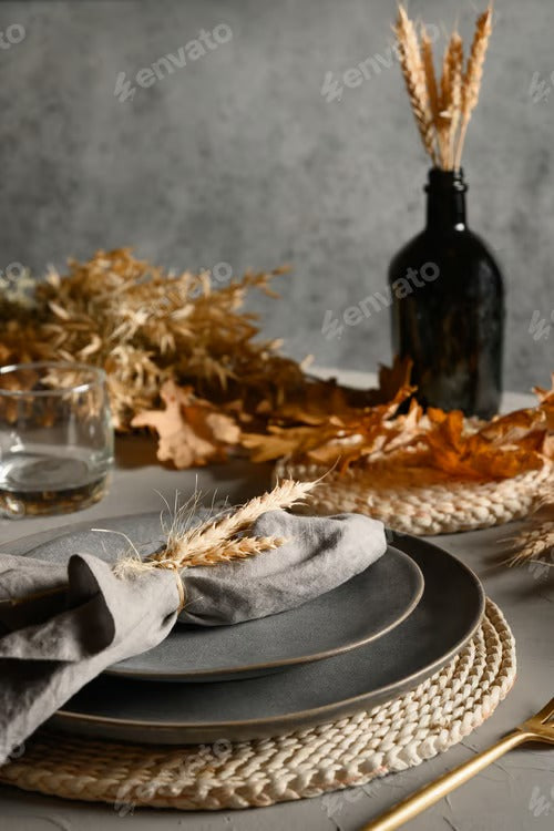 Autumn table setting with dry yellow oak leaves, fall decoration on grey table. Thankisgiving day