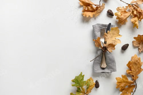 Elegant fall oak leaves as frame and cutlery on white. View from above, space for design. Catering.