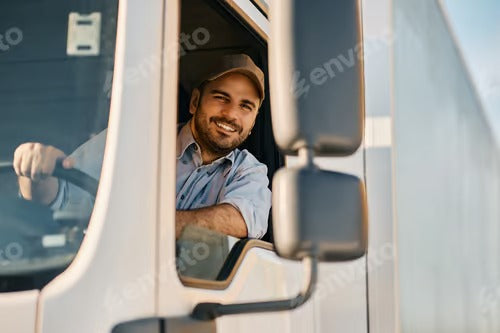 Happy truck driver looking through side window while driving his truck.