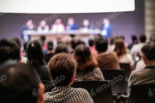 Rear view of Audience in the conference hall or seminar meeting which have Speakers