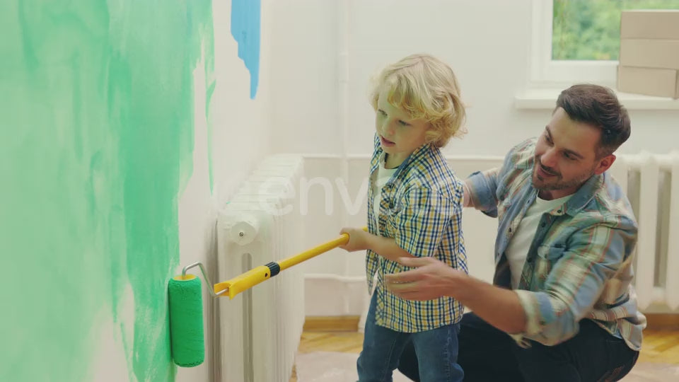 Father and Son Painting a Wall in Their Home with a Roller