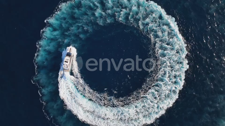 Top down drone shot of luxury yacht driving in a circle at sea while zooming out